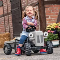 Young girl in red wellies smiling whilst sitting on tractor ride-on toy